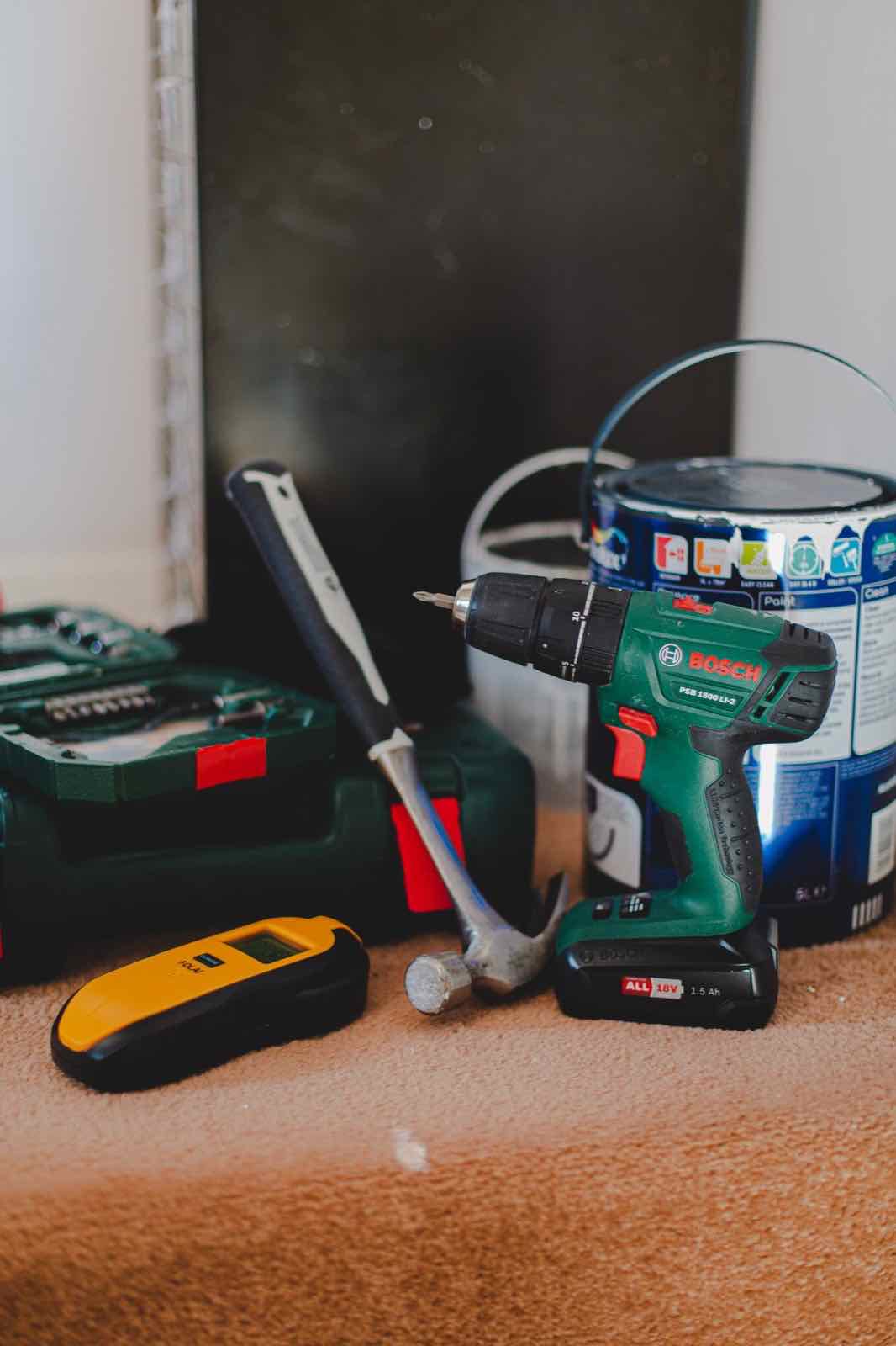 Assorted handyman tools including a drill, hammer, and paint supplies