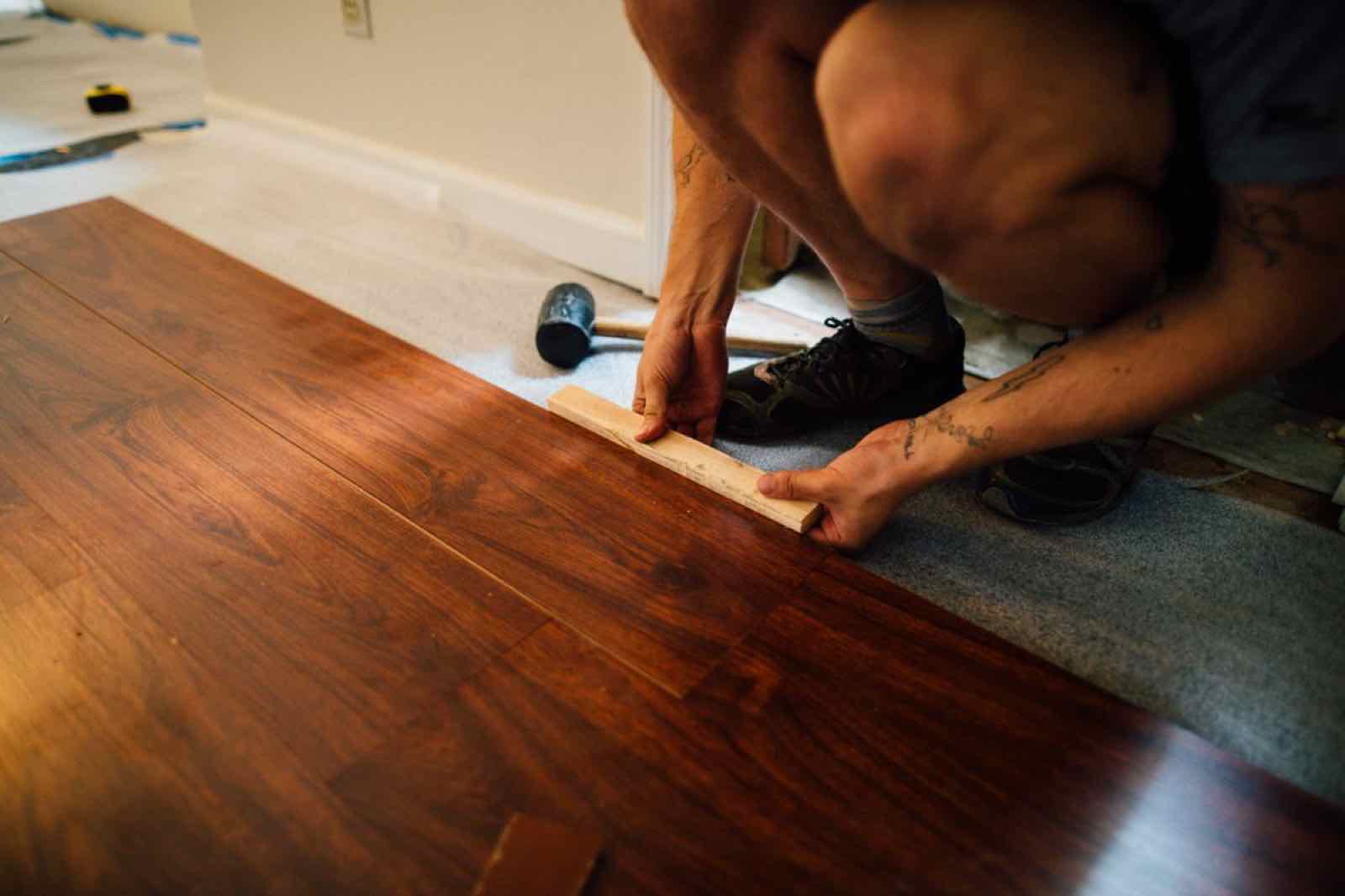 Installer fitting a plank of laminate flooring